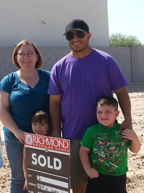 Family of four holding "SOLD" home sign