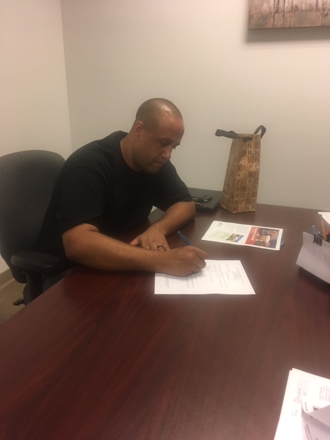 Person signing paperwork at office desk