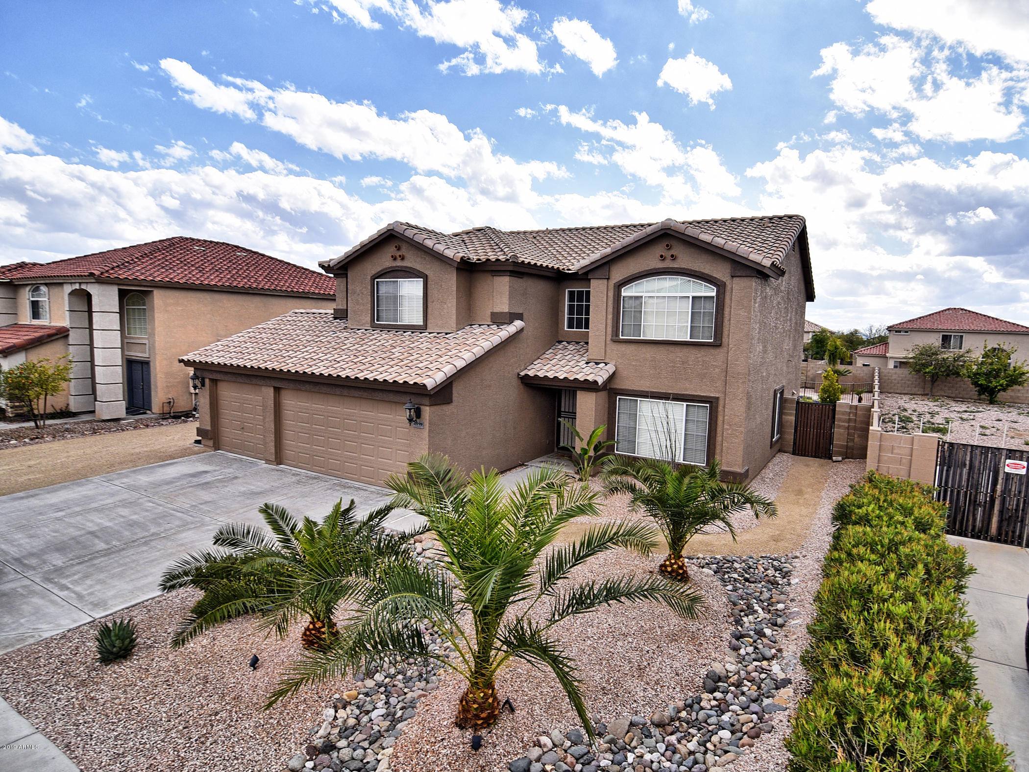 Two-story stucco house with palm landscaping