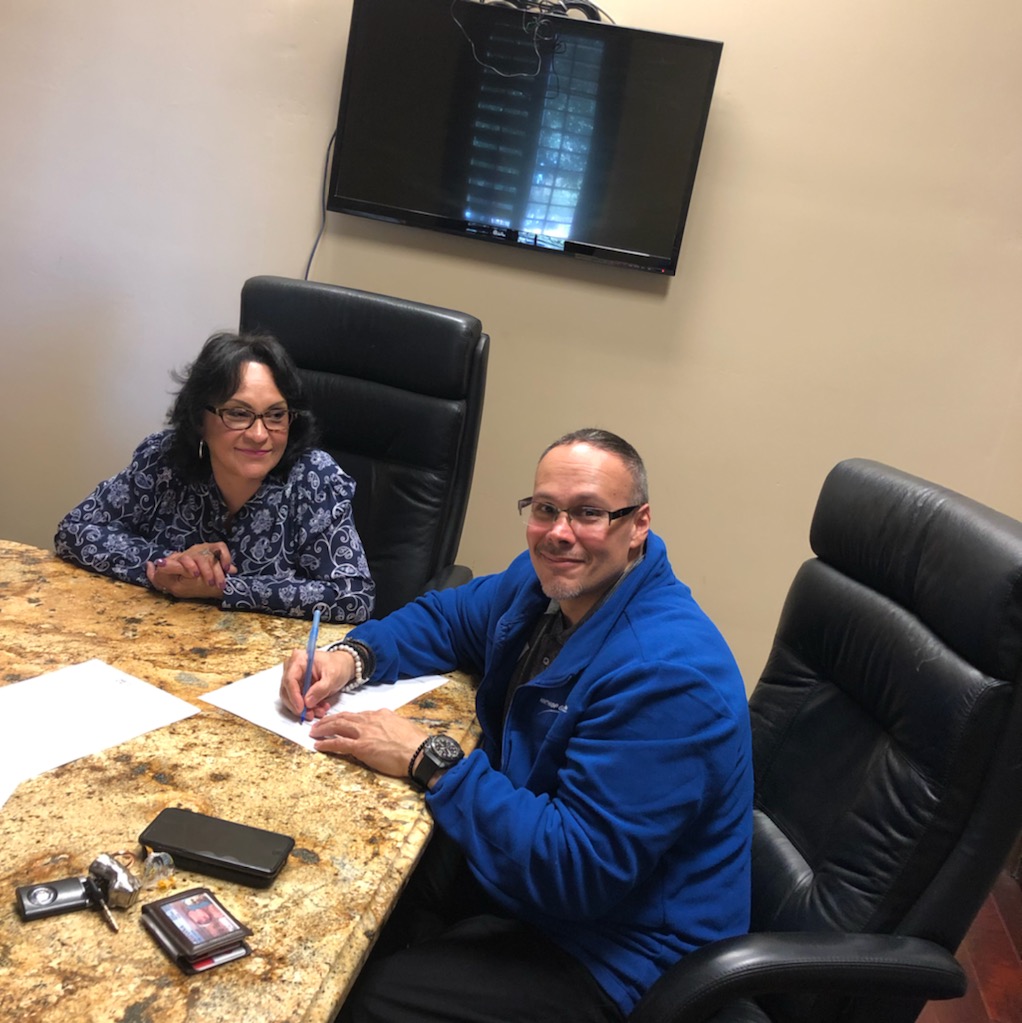 Two people signing documents at conference table