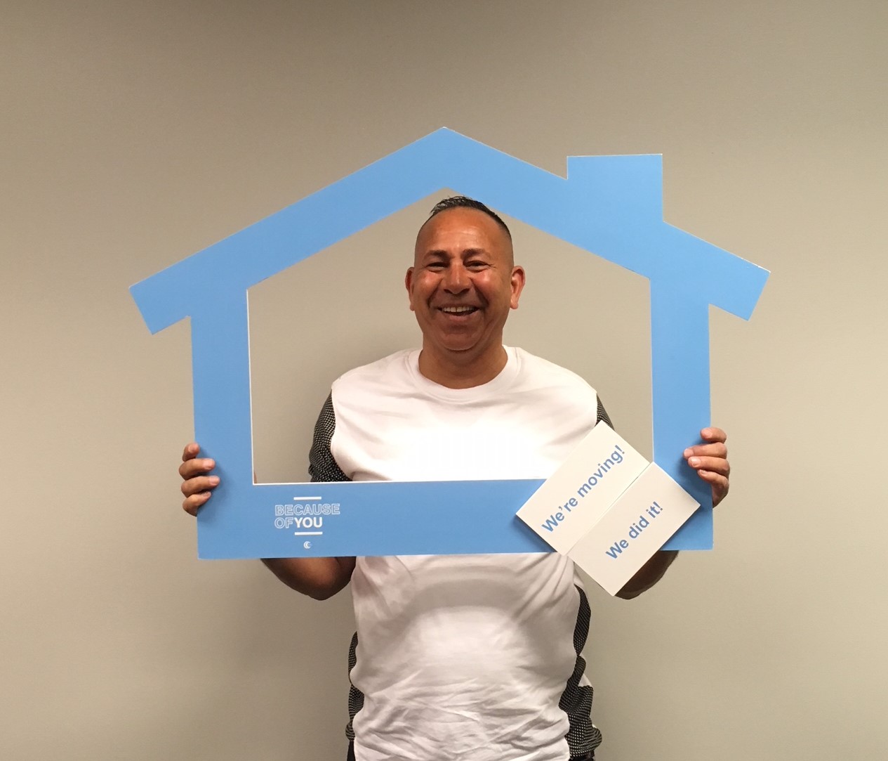 Smiling man holding blue house-shaped frame